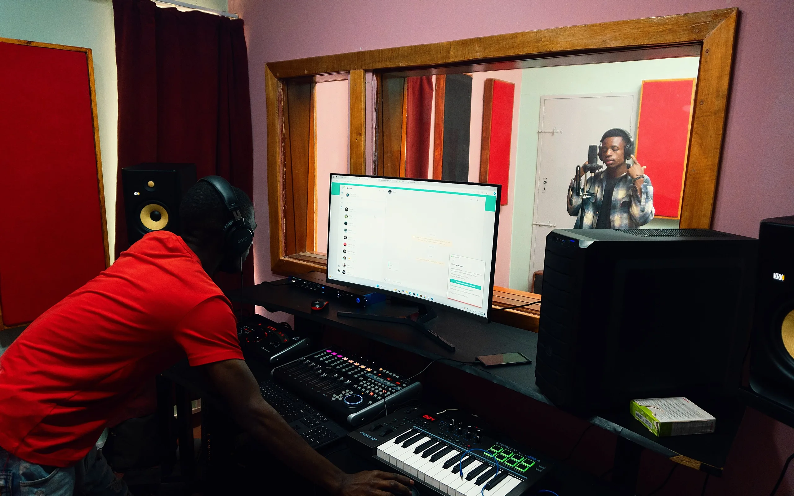 Un ingénieur du son montre une console à la personne qu'il forme, dans un studio lumineux